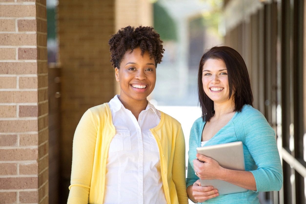 Two women standing next to each other holding a tablet.